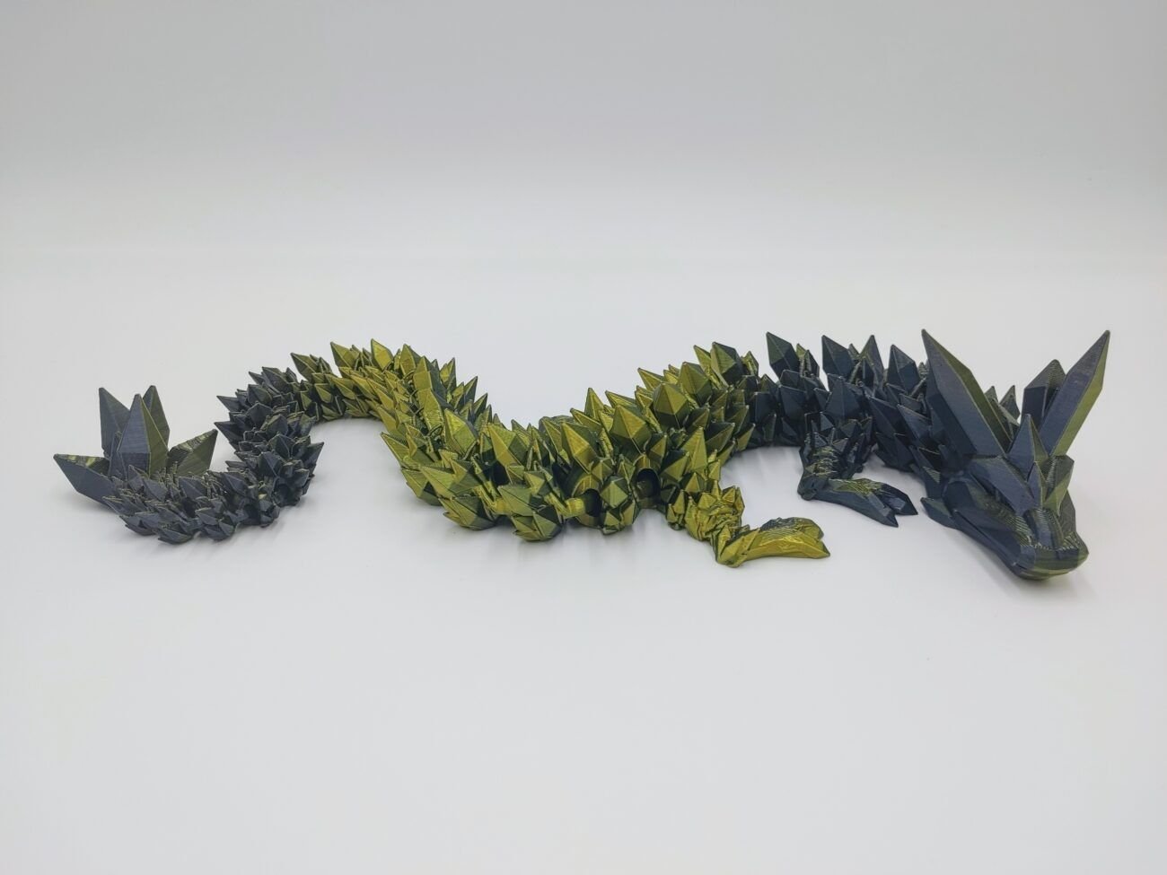 Articulated Crystal Dragon 3D Printed in Black to Gold Articulated Crystal Dragon Sensory Toy Designed by Cinderwing3d in Black to Gold with a White Background