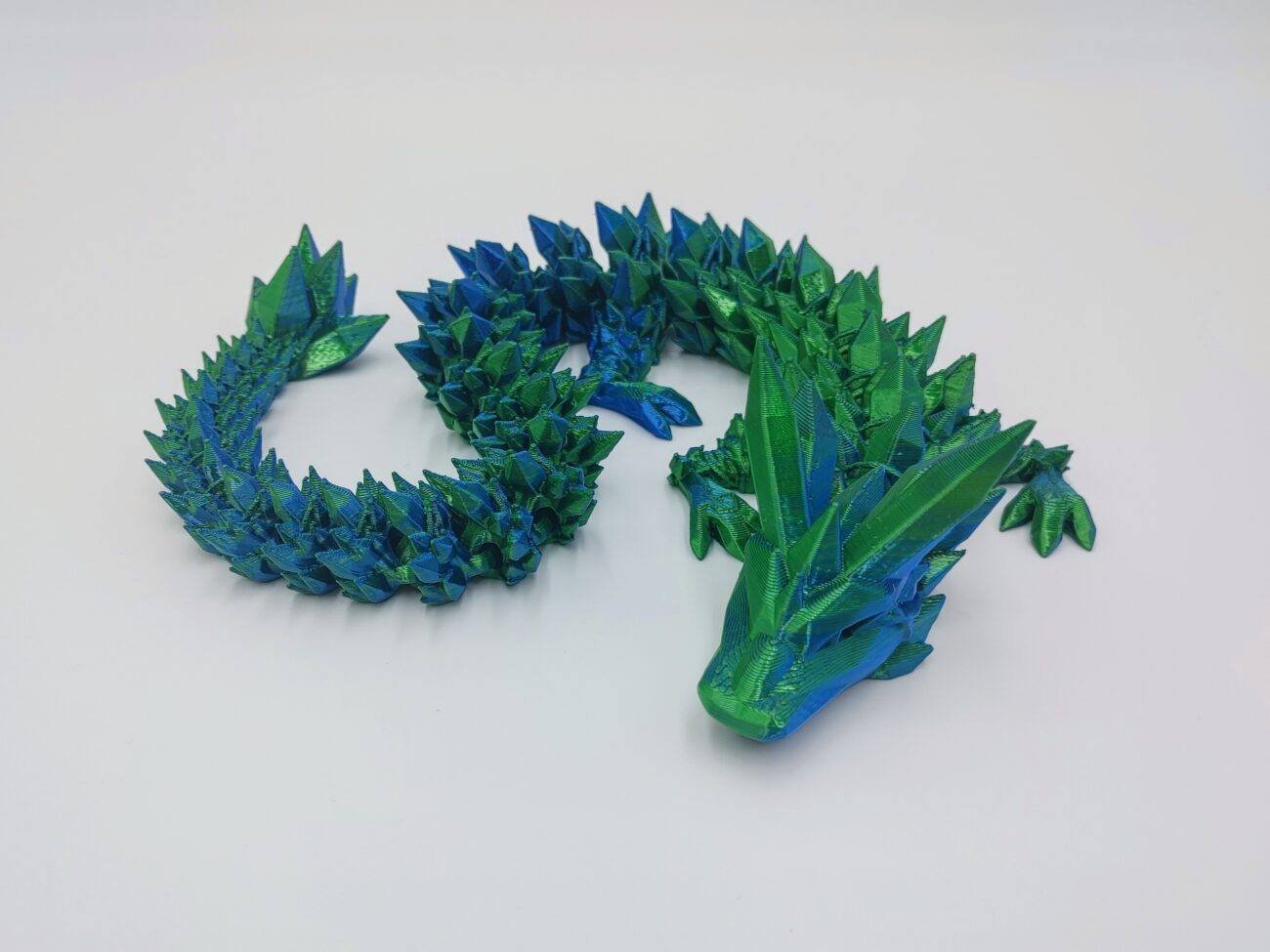 Articulated Crystal Dragon 3D Printed in Blue to Green Articulated Crystal Dragon Sensory Toy in Silk Blue to Green with a White Background