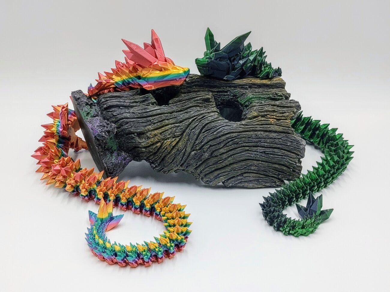 Articulated Crystal Dragon 3D Printed in Coober Pedy Rainbow and Black to Green Articulated Crystal Dragon Sensory Toys in Silk Coober Pedy Rainbow and Black to Green Sitting on a Log with a White Background