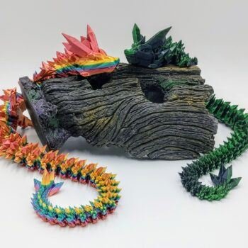 Articulated Crystal Dragon 3D Printed in Coober Pedy Rainbow and Black to Green Articulated Crystal Dragon Sensory Toys in Silk Coober Pedy Rainbow and Black to Green Sitting on a Log with a White Background
