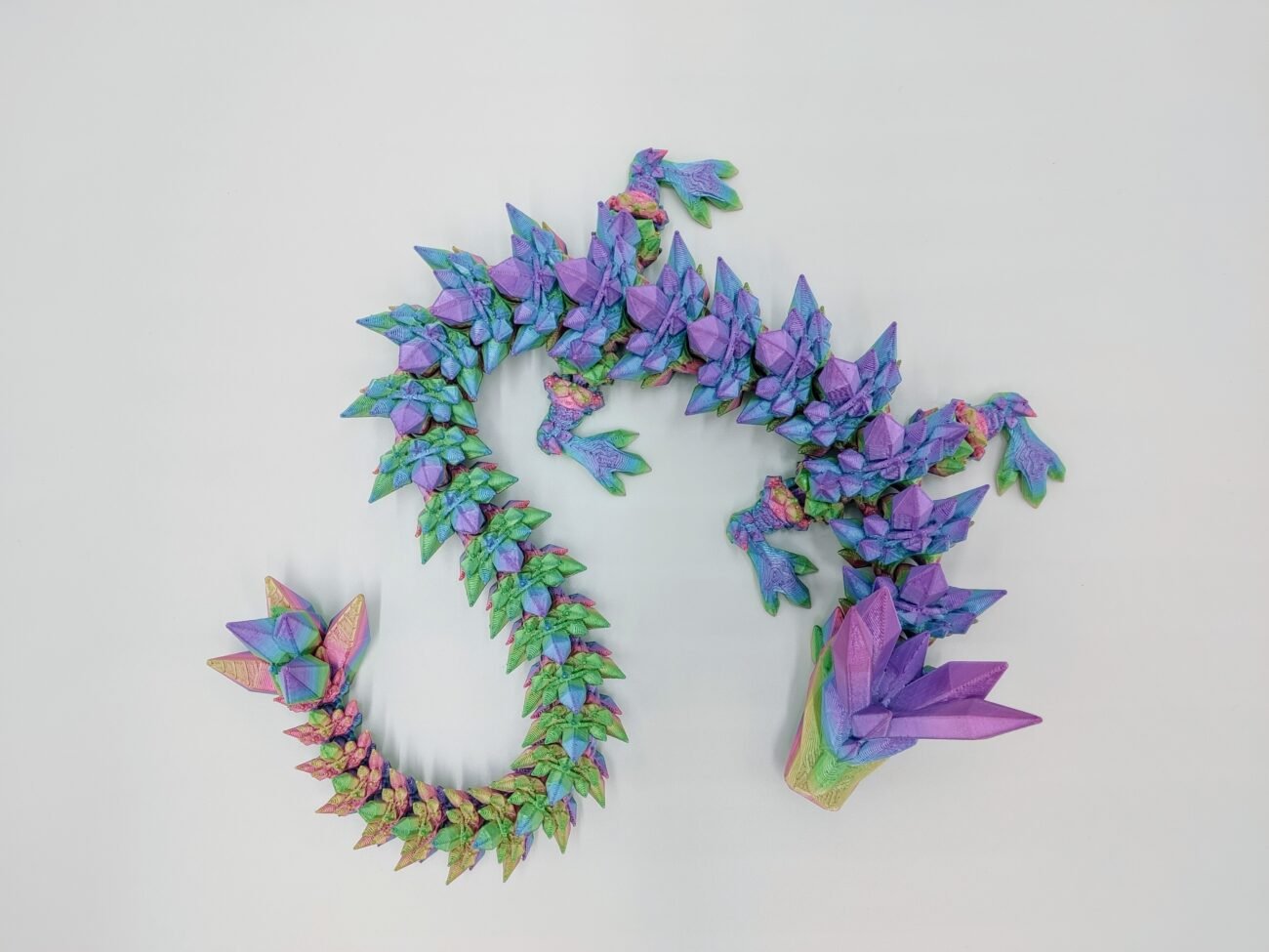 Articulated Crystal Dragon 3D Printed in Fairy Floss Rainbow Articulated Crystal Dragon Sensory Toy Designed by Cinderwing3d in Fairy Floss Rainbow taken from Above with a White Background