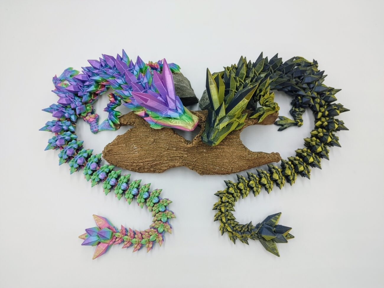 Articulated Crystal Dragon 3D Printed in Great Barrier Reef Rainbow and Black to Gold Articulated Crystal Dragon Sensory Toys in Silk Great Barrier Reef Rainbow and Black to Gold Sitting on a Log from Above with a White Background