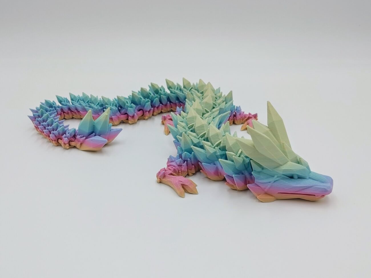 Articulated Crystal Dragon 3D Printed in Matte Pastal Rainbow Articulated Crystal Dragon Sensory Toy Designed by Cinderwing3d in Matte Pastal Rainbow with a White Background