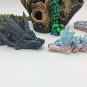 Articulated Crystal Dragons 3D Printed in Uluru Rainbow and Black to Gold Articulated Crystal Dragon Sensory Toys in Silk Uluru Rainbow and Black to Gold with a White Background Looking at Each Other