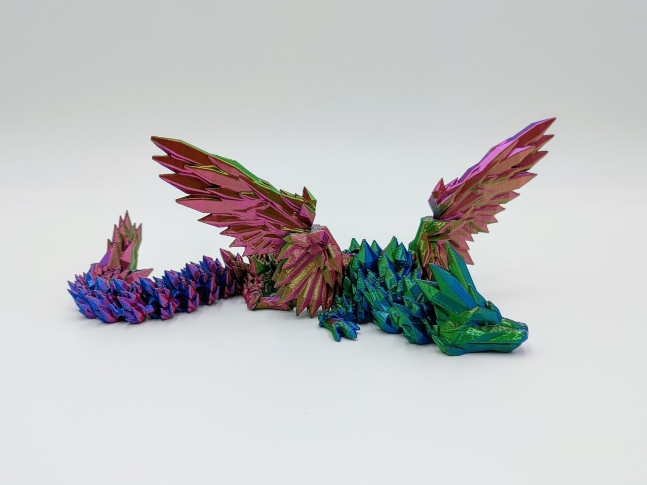 Articulated Crystalwing Dragon 3D Printed in a Silk Tri Colour Articulated Crystalwing Dragon Sensory Toys in a Silk Tri Colour with a White Background
