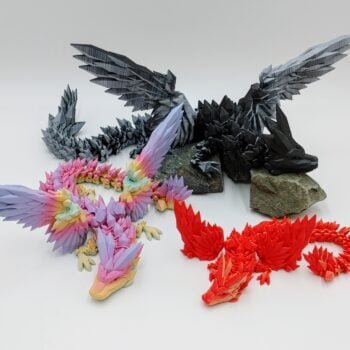 Articulated Crystalwing Dragon 3D Printed in Matte Dual Tone Hues and Rainbows Articulated Crystalwing Dragon Sensory Toys in Matte Dual Tone Hues and Rainbows Sitting on Rocks with a White Background