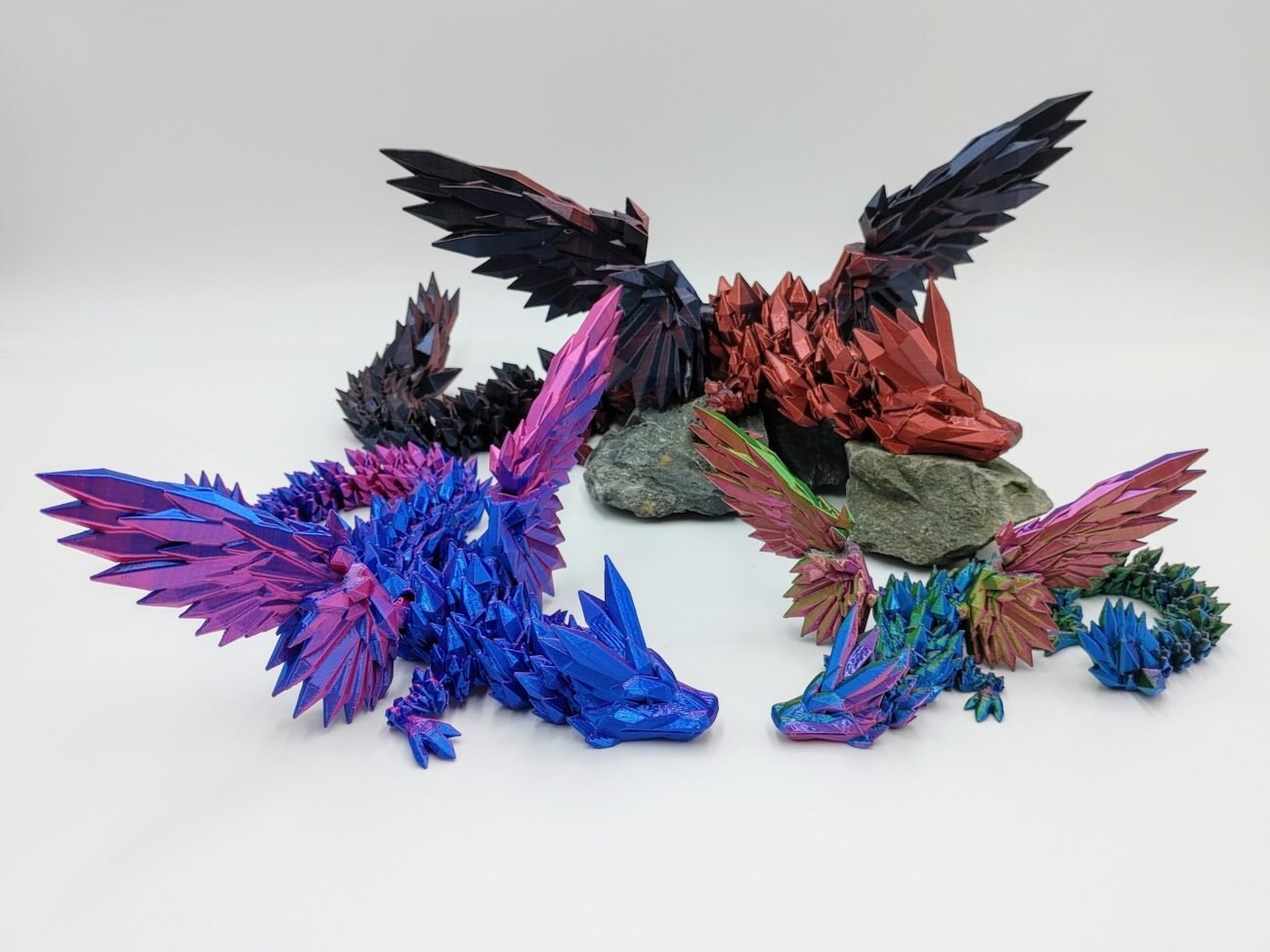 Articulated Crystalwing Dragon 3D Printed in Silk Multi Tone Hues Articulated Crystalwing Dragon Sensory Toys in Silk Multi Tone Hues Sitting on Rocks with a White Background