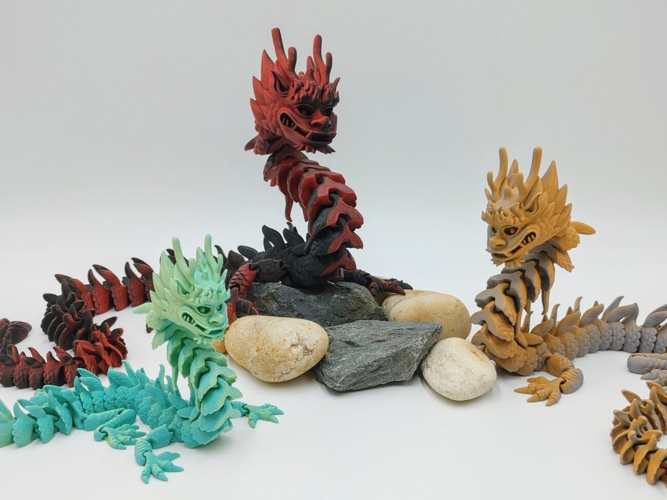 Articulated Imperial Dragon 3D Printed in Matte Multi Tone Hues Articulated Imperial Dragon Sensory Toys in Matte Multi Tone Hues Sitting on Rocks Closeup with a White Background