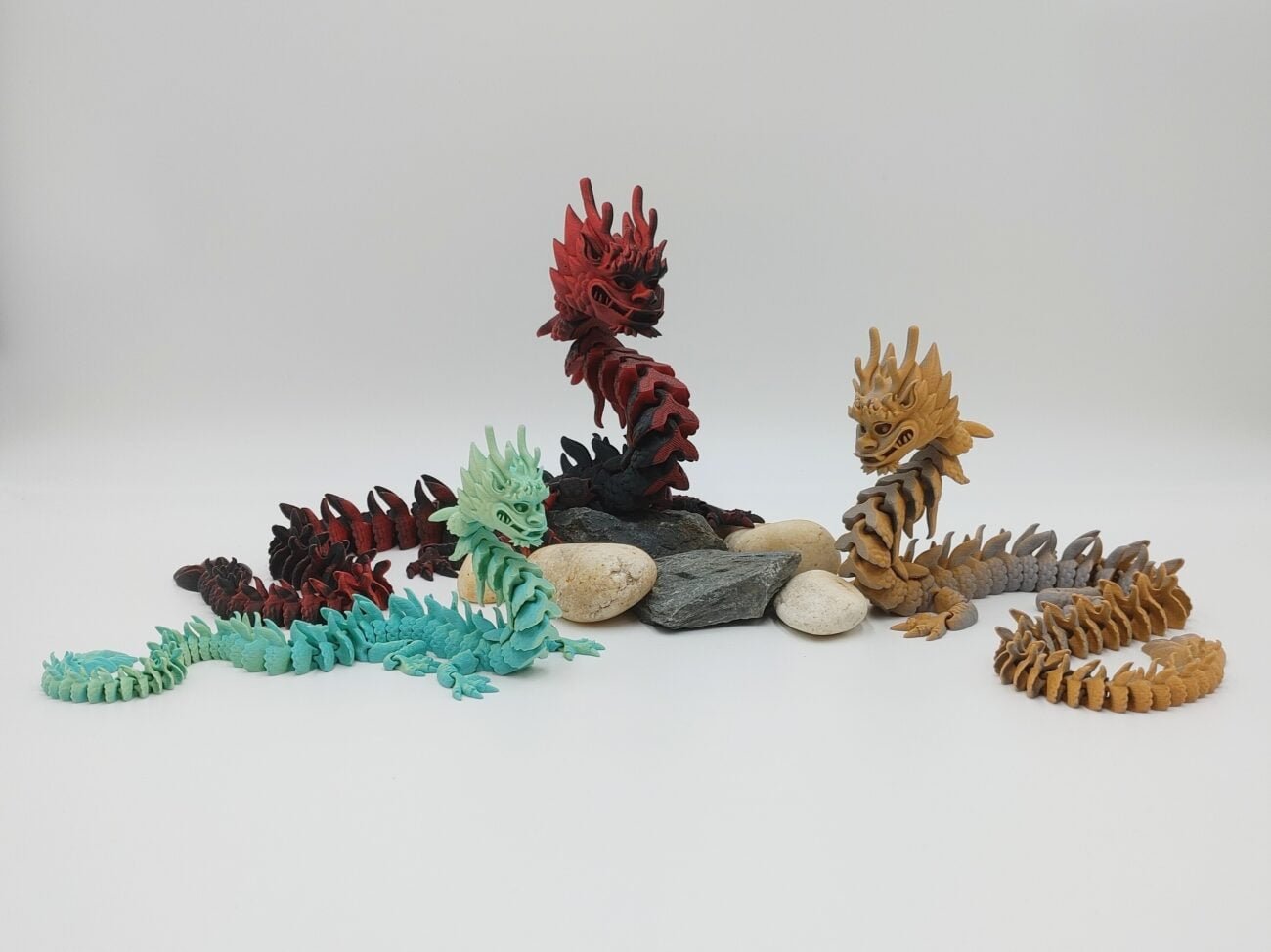 Articulated Imperial Dragon 3D Printed in Matte Multi Tone Hues Articulated Imperial Dragon Sensory Toys in Matte Multi Tone Hues Sitting on Rocks with a White Background