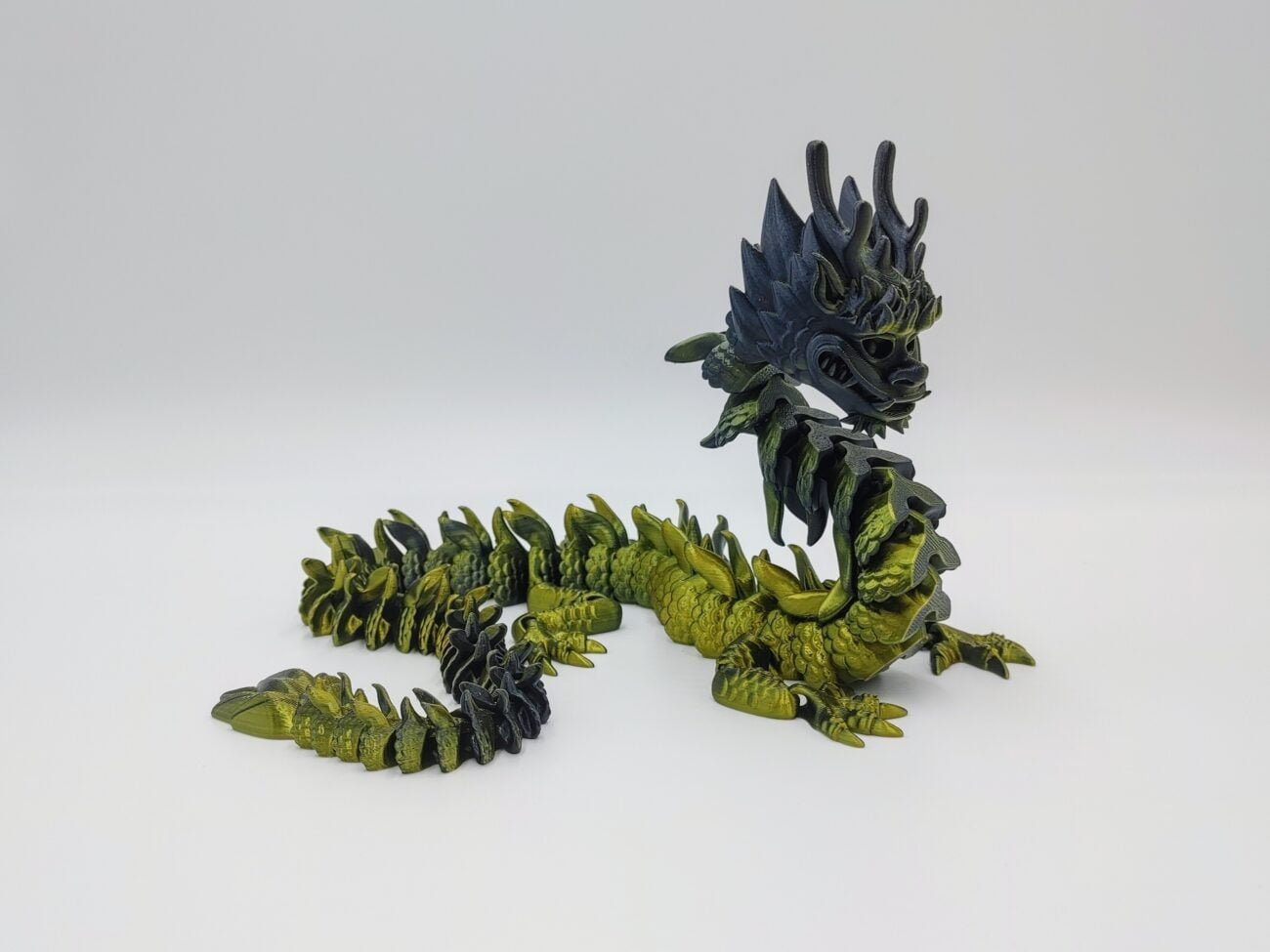 Articulated Imperial Dragon 3D Printed in Silk Gold to Black Articulated Imperial Dragon Sensory Toys Designed by Flexy Factory in Silk Gold to Black with a White Background