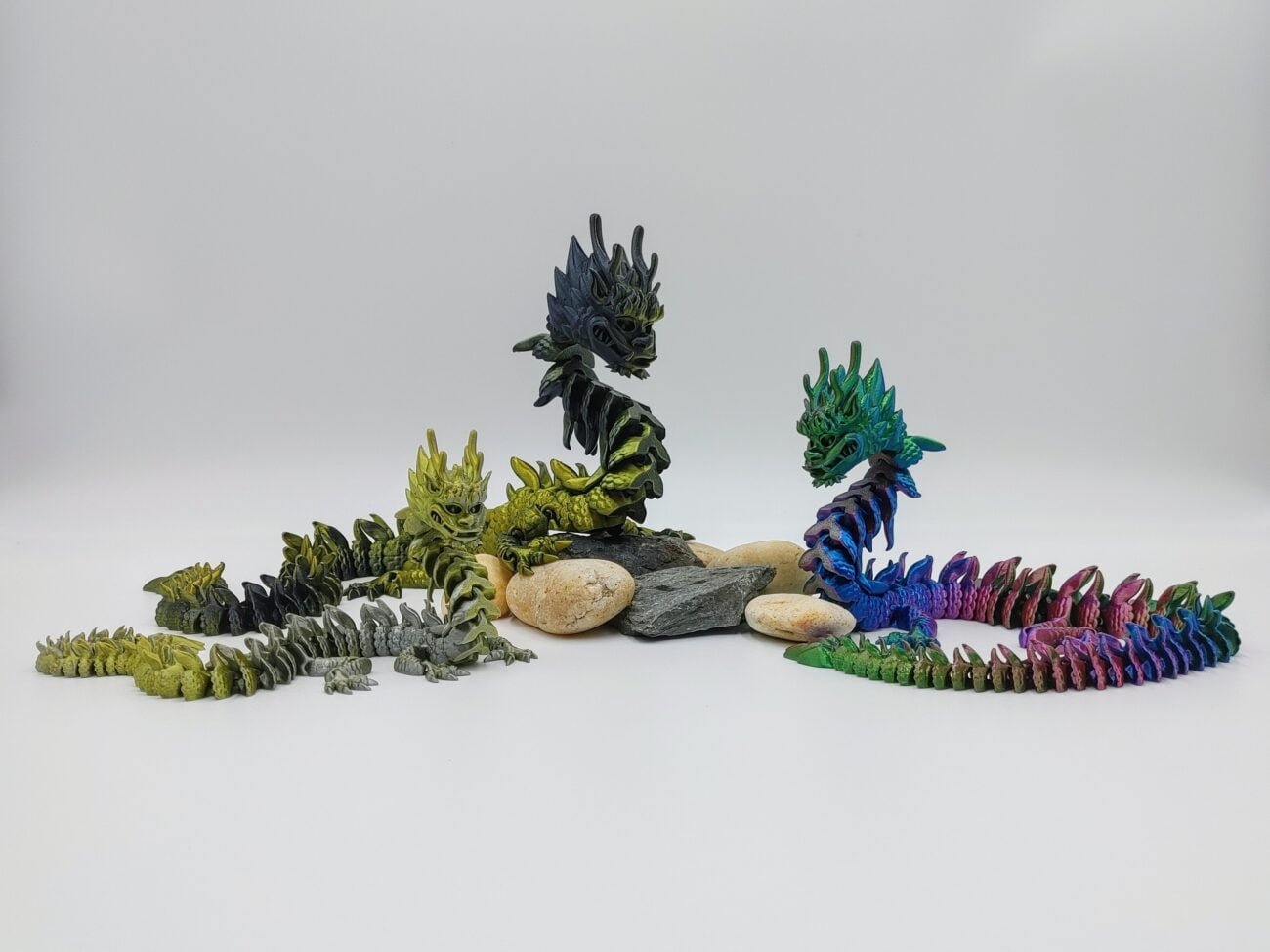 Articulated Imperial Dragon 3D Printed in Silk Multi Tone Hues Articulated Imperial Dragon Sensory Toys in Silk Multi Tone Hues Sitting on Rocks with a White Background