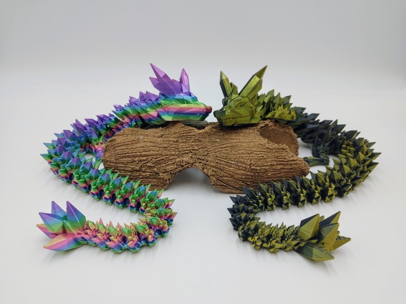 Articulated Crystal Dragon Sensory Toys in Silk Great Barrier Reef Rainbow and Black to Gold Sitting on a Log with a White Background